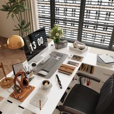 an office desk with a computer, keyboard and mouse on it in front of large windows