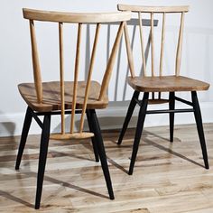 two wooden chairs sitting side by side on top of a hard wood floor next to each other