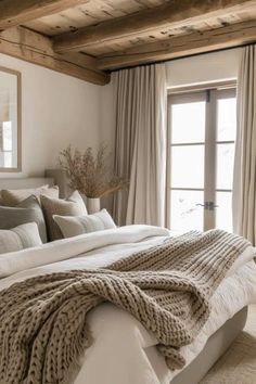 a large bed sitting under a window next to a wooden beam in a living room