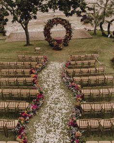 an outdoor ceremony setup with flowers and petals on the aisle, surrounded by wooden chairs