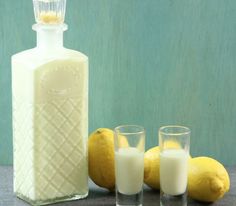 a bottle of milk next to three glasses with lemons