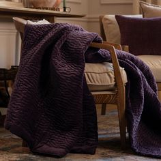 a purple blanket sitting on top of a wooden chair