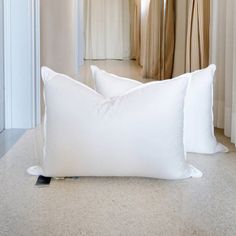 two white pillows sitting on top of a floor