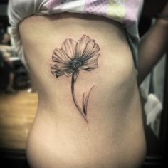 a woman's stomach with a flower tattoo on her side ribcage,