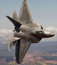 a fighter jet flying through the air with mountains in the background