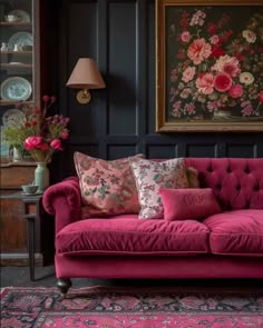 a living room with pink couches and flowers on the wall behind it, along with other furniture