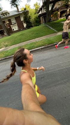 a man and woman are playing frisbee in the street while two other people run behind them