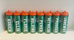 six green and orange sports bottles sitting next to each other on a white countertop