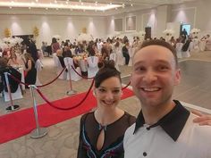 a man and woman standing next to each other in front of a banquet room full of people