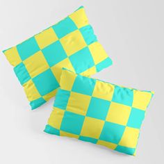 two blue and yellow checkered pillows sitting on top of each other in front of a white background