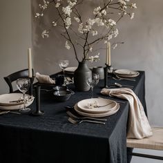 a dining table set with black linens and white flowers