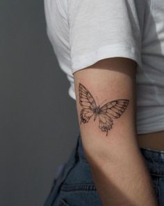 a small butterfly tattoo on the left upper arm and lower arm, which is black and white