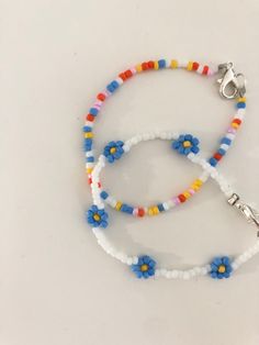 two bracelets with flowers on them sitting on a white surface, one is blue and the other is red