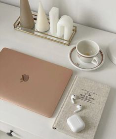 an apple laptop computer sitting on top of a white desk next to a cup and saucer