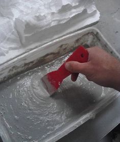 a person is using a red brush to clean the surface of a sink with white foam on it