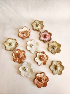 several different types of flower shaped buttons on a white tablecloth with one button in the middle