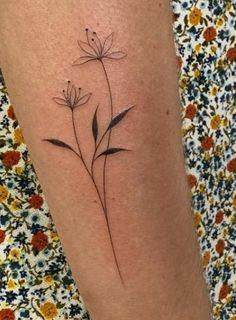 a woman's leg with a small flower tattoo on the left side of her arm