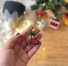 a hand holding an ornament in front of a table with christmas decorations on it