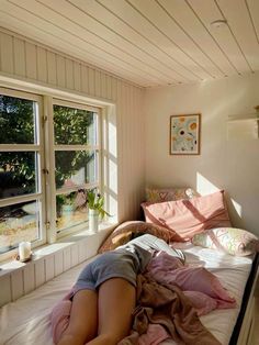 a woman laying on top of a bed next to a window