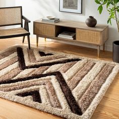 a living room area with a rug, chair and potted plant