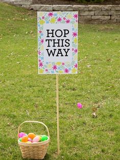 a sign that says hop this way next to a basket with easter eggs in it