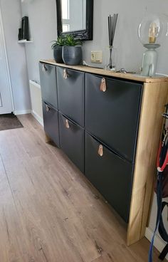 a black cabinet with drawers and plants on top