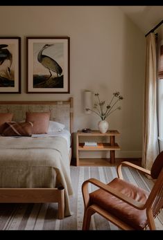 a bedroom with two paintings on the wall and a bed in front of a window