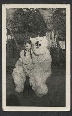 an old black and white photo of a boy hugging a polar bear