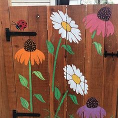 a wooden fence painted with flowers and ladybugs