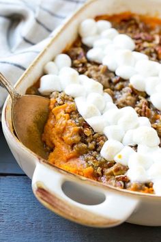 sweet potato casserole with marshmallows in a white dish on a wooden table