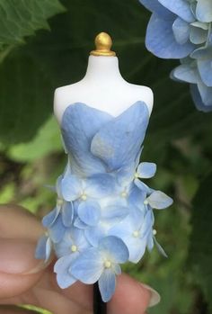 a mannequin with blue flowers on it being held by a person's hand