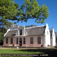 a large white house sitting under a tree