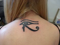 an eye tattoo on the back of a woman's shoulder