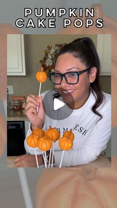 a woman is holding up pumpkins on a stick with the words pumpkin cake pops in front of her