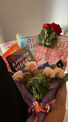 a person holding a bouquet of roses in their left hand and several books on the other