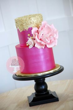 a pink and gold cake with flowers on top