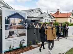 people are walking down the sidewalk in front of some houses