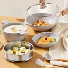 a table topped with bowls and pans filled with food