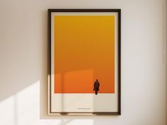 an orange and yellow poster hangs on the wall next to a black framed art piece