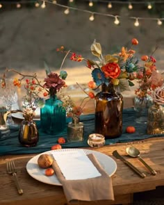 the table is set with plates and vases filled with flowers, candles and napkins