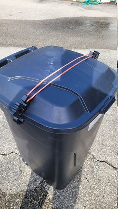 a blue trash can sitting on top of a sidewalk