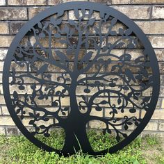 a metal tree sculpture sitting in front of a brick wall