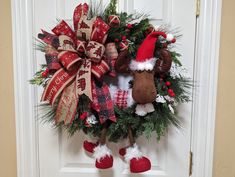 a christmas wreath hanging on the front door with santa hats and reindeer feet attached to it