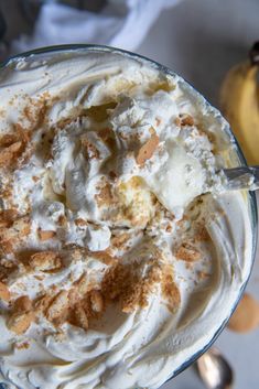 a close up of a dessert in a glass bowl with whipped cream and nuts on top