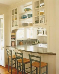 a large kitchen with wooden floors and white walls, along with lots of shelves on the wall