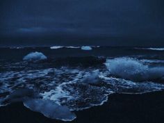 icebergs floating in the ocean on a dark night with blue sky and clouds