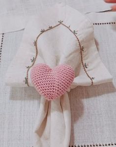 a crocheted pink heart on a white cloth