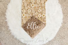 a tie with the name ellie on it is laying on a white fur rug next to a pair of scissors