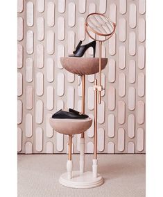 a pair of high heeled shoes sitting on top of a round stand in front of a wall