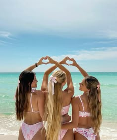 three beautiful young women standing on top of a beach